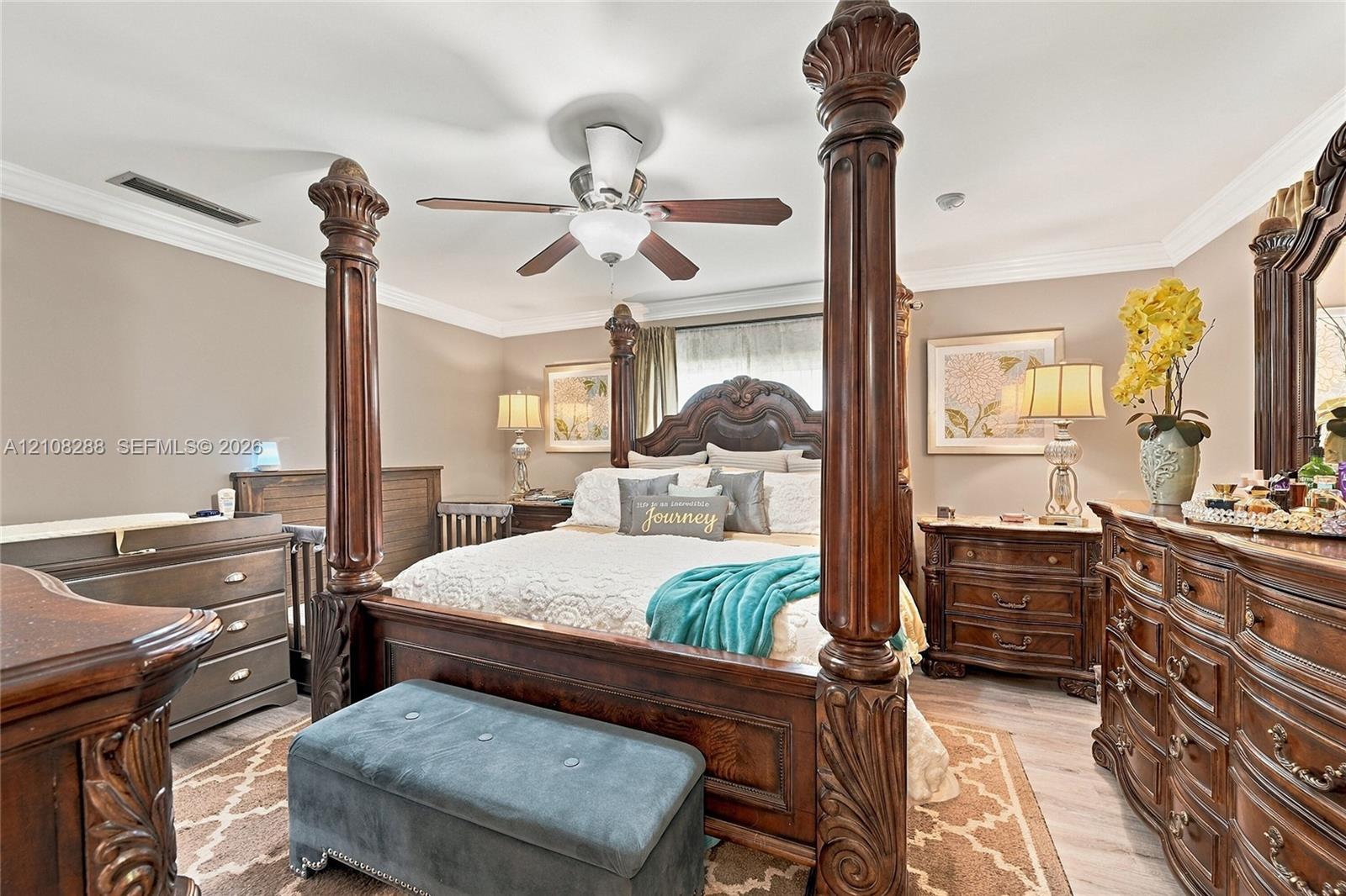 Bedroom interior featuring crown molding, neutral wall paint, and a ceiling-mounted fan with integrated lighting