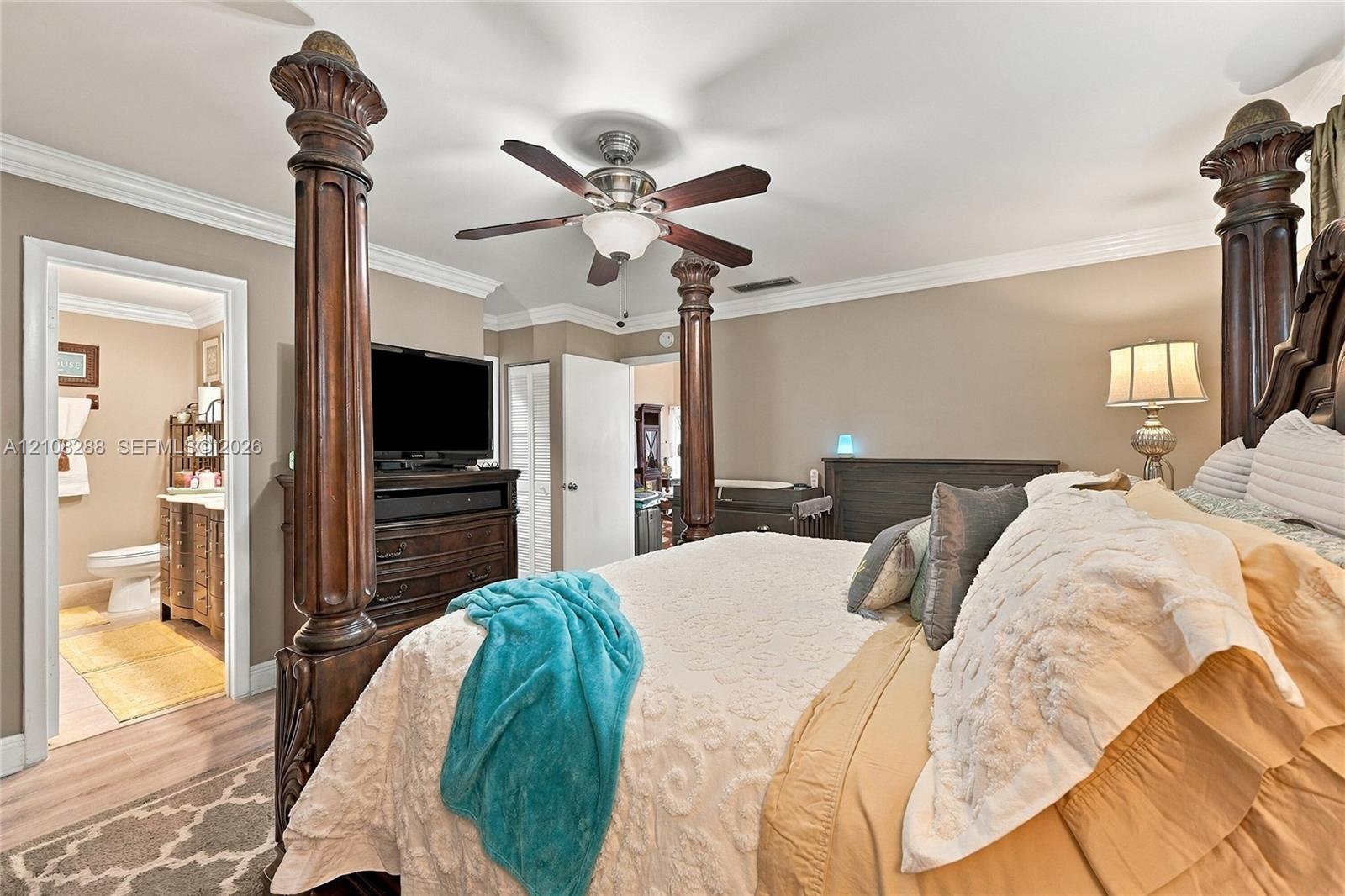Neutral-toned walls featuring crown molding, wood-finish flooring, and a ceiling fan with integrated lighting
