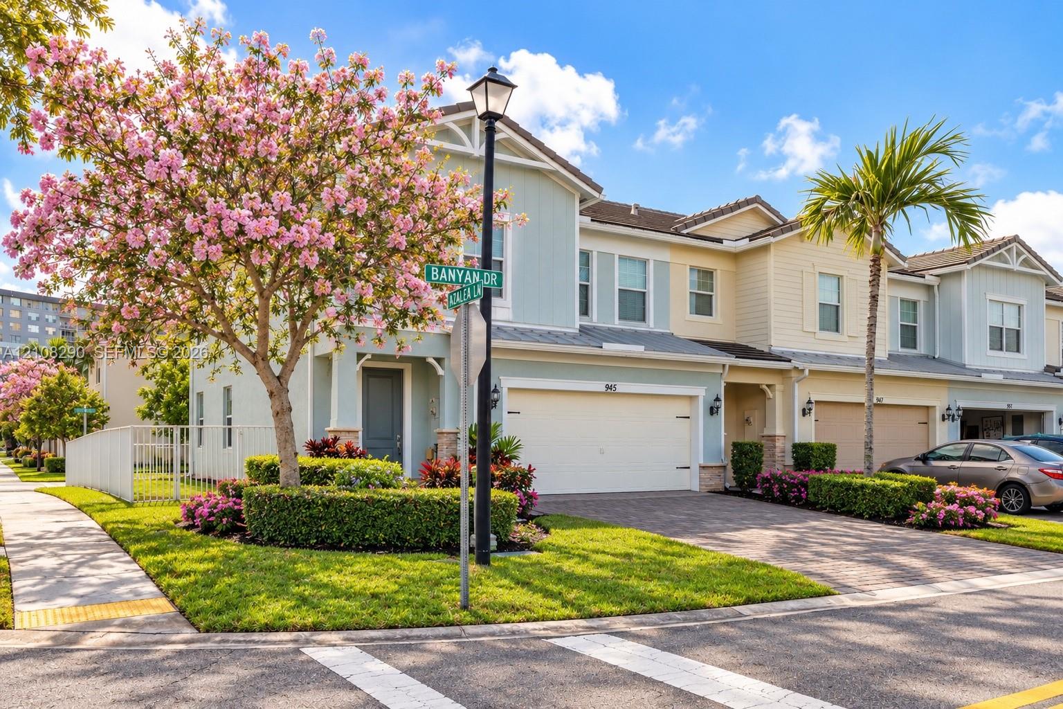 Two-story townhome exterior featuring shiplap-style siding, a multi-tone facade, a paved driveway, and an attached two-car garage Two-story townhome exterior featuring shiplap-style siding, a multi-tone facade, a paved driveway, and an attached two-car garage