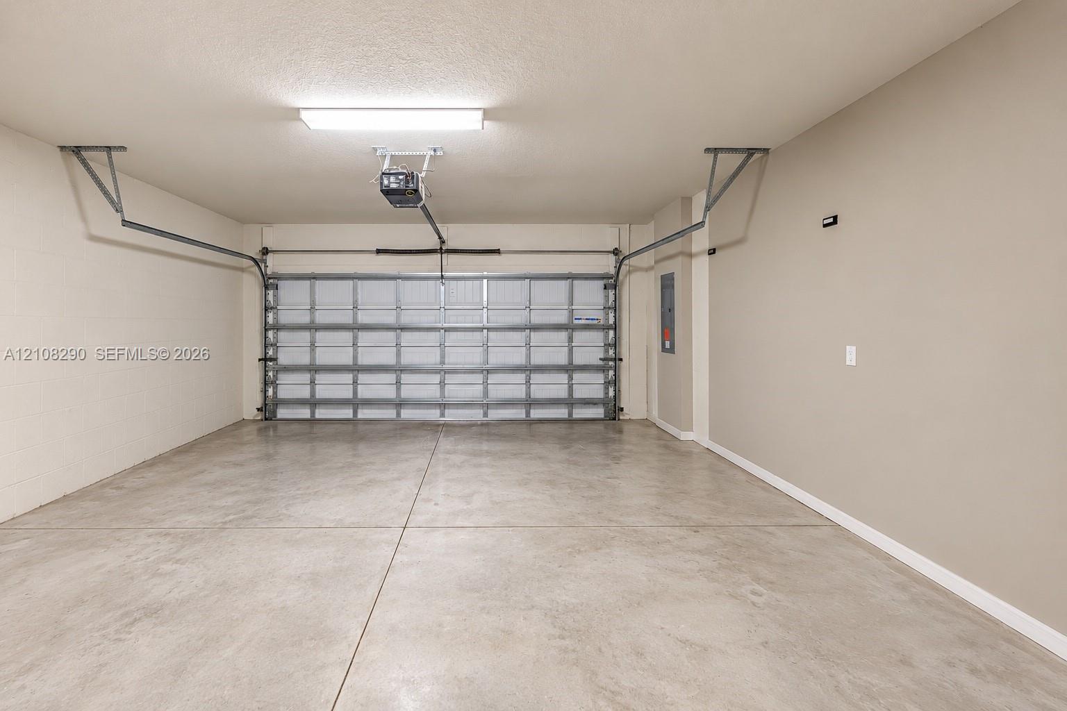 Two-car garage featuring a concrete floor, finished walls, overhead lighting, and an automated door opener