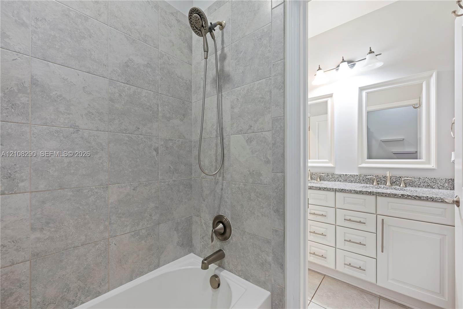 Shower area featuring stone-look wall tile and a multi-setting handheld showerhead