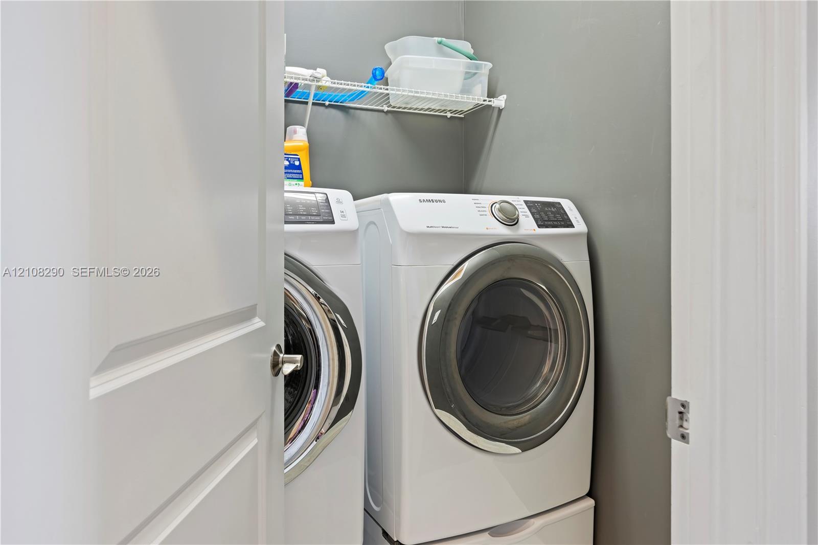 Laundry area featuring a side-by-side washer and dryer set with pedestal bases and a mounted wire shelving unit Laundry area featuring a side-by-side washer and dryer set with pedestal bases and a mounted wire shelving unit