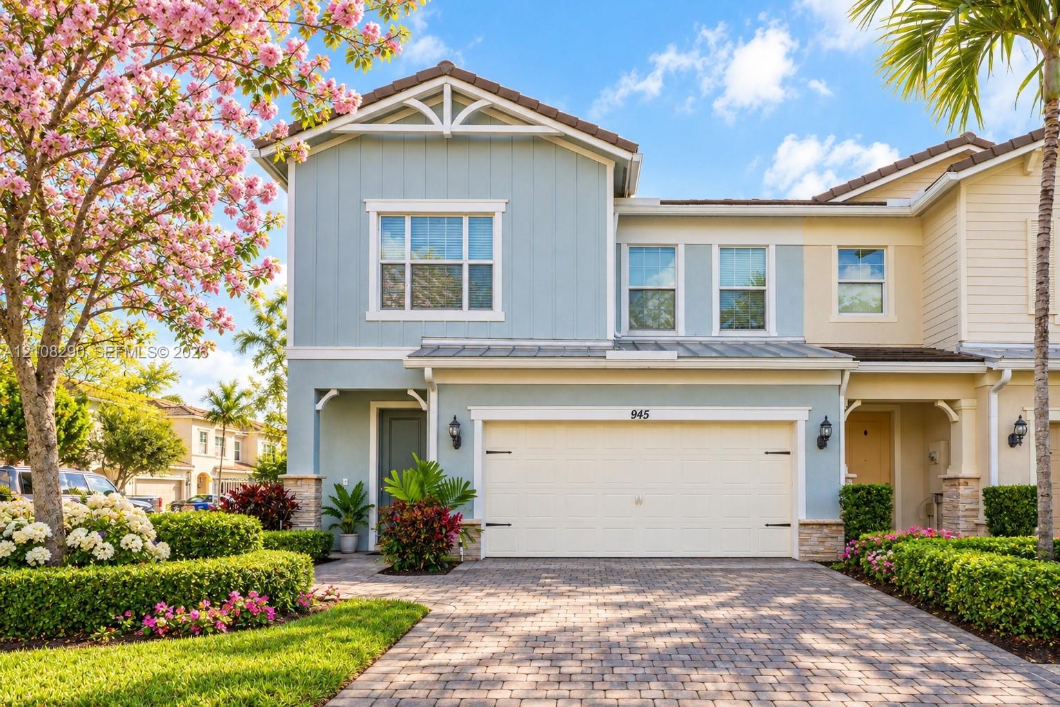 Two-story residence featuring vertical siding, a paver driveway, an attached two-car garage, stone veneer accents, and decorative gable brackets Two-story residence featuring vertical siding, a paver driveway, an attached two-car garage, stone veneer accents, and decorative gable brackets