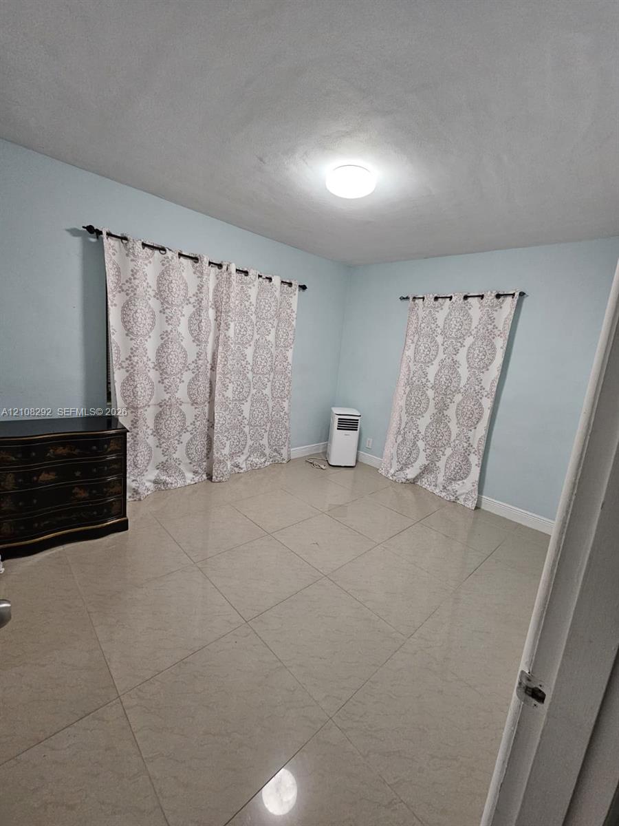 Light-filled room featuring large-format tile flooring and neutral wall paint