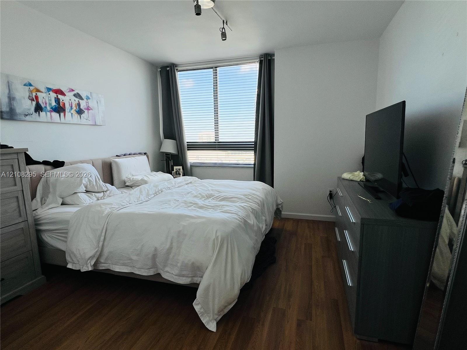 Large window featuring horizontal blinds, wood-finish flooring, and multi-directional track lighting