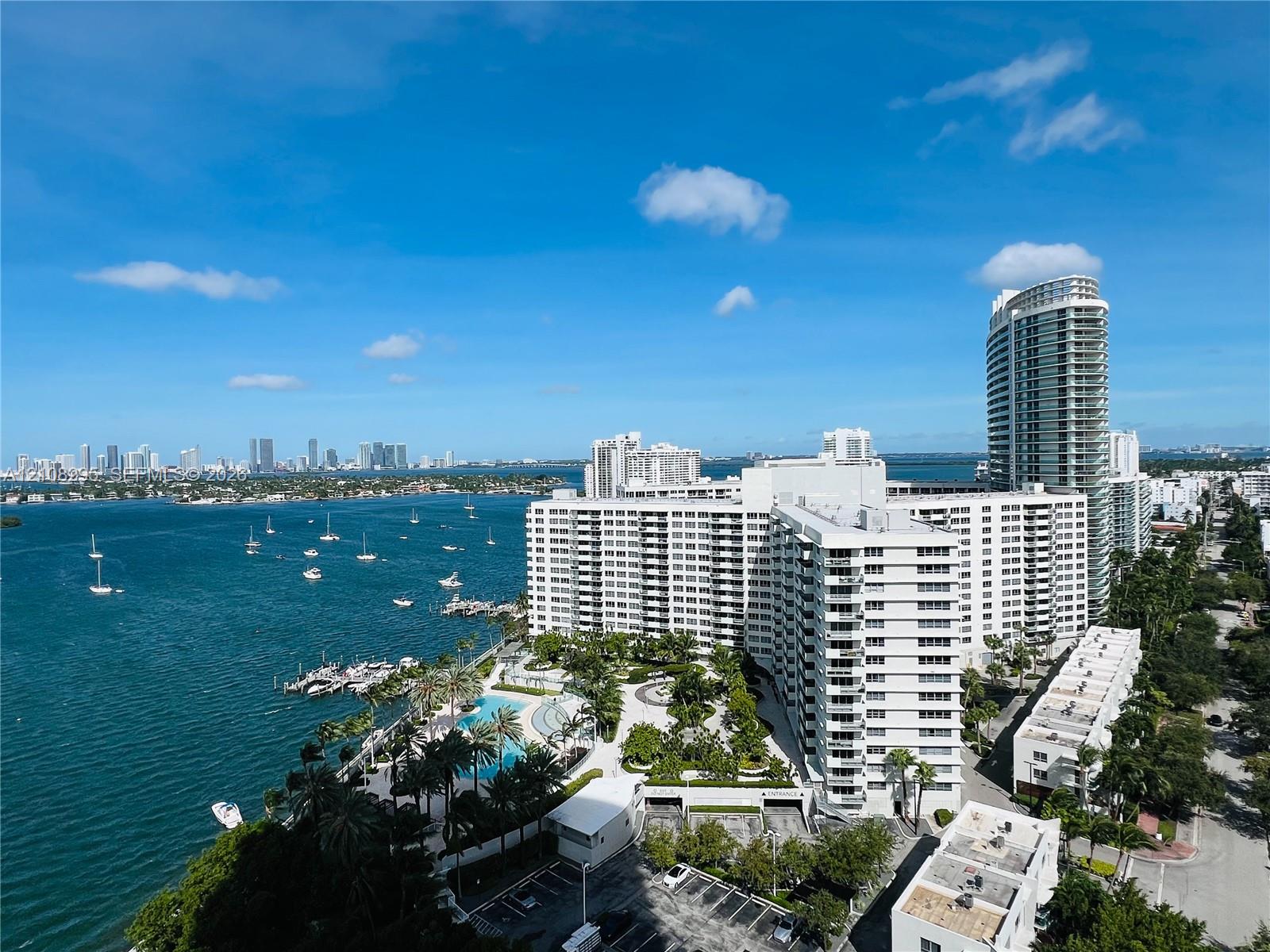 High-rise residential exterior with waterfront orientation, featuring an outdoor swimming pool, paved pedestrian pathways, lush landscaping, and integrated parking facilities High-rise residential exterior with waterfront orientation, featuring an outdoor swimming pool, paved pedestrian pathways, lush landscaping, and integrated parking facilities