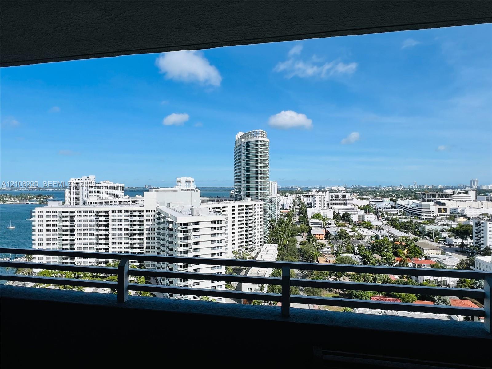 Covered balcony with a metal railing, providing an expansive outlook over the urban skyline and adjacent waterway Covered balcony with a metal railing, providing an expansive outlook over the urban skyline and adjacent waterway