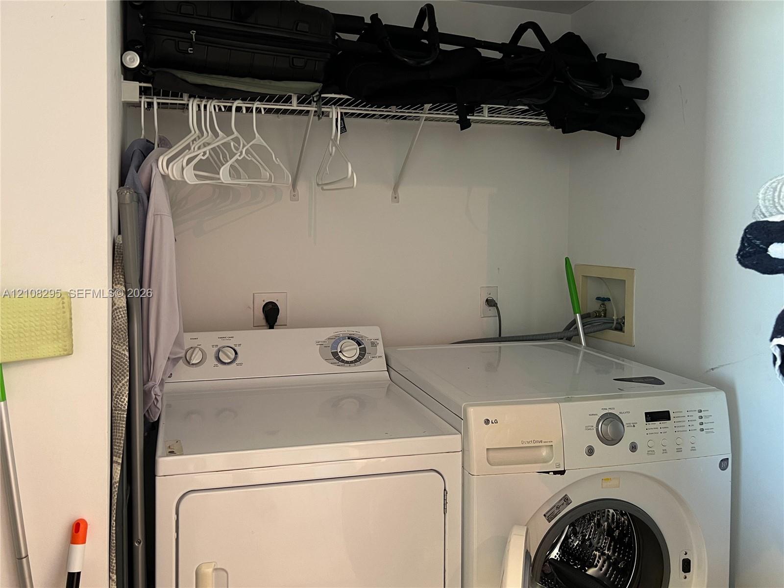 Dedicated laundry area featuring a white front-load washer and a top-load dryer, complemented by a white wire overhead shelving system