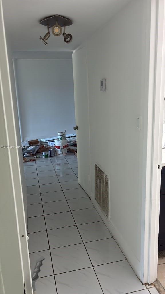 Hallway featuring light-toned tile flooring and a metallic three-light adjustable track fixture