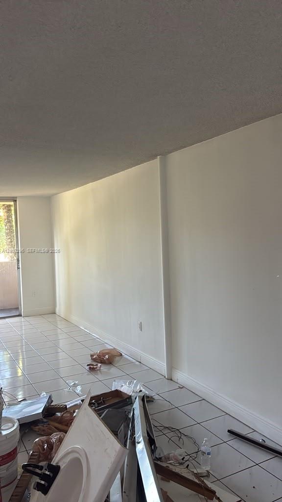 Interior space featuring white-toned tile flooring and an exterior glass door