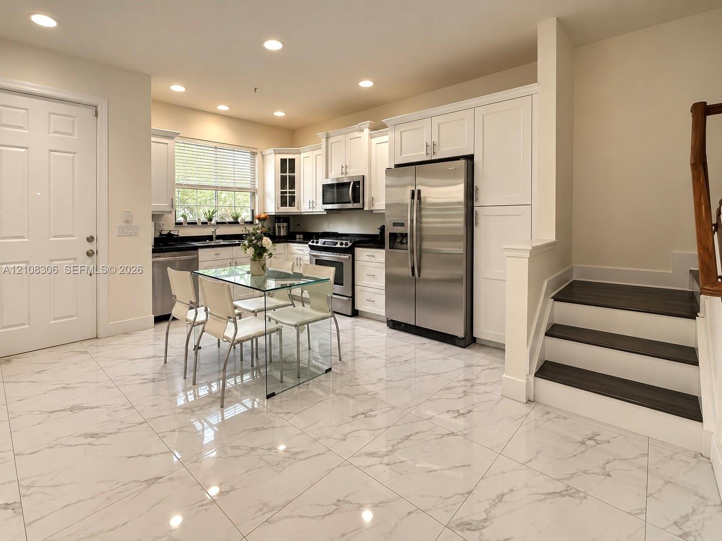 Kitchen featuring large-format tile flooring, white cabinetry, dark stone countertops, stainless steel appliances, and recessed lighting