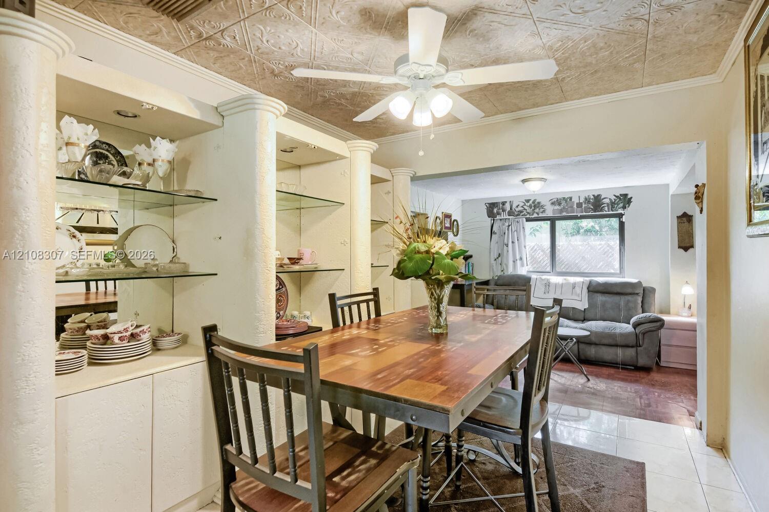 Custom built-in cabinetry with glass shelving and mirrored backing, decorative ceiling tiling, and architectural columns Custom built-in cabinetry with glass shelving and mirrored backing, decorative ceiling tiling, and architectural columns