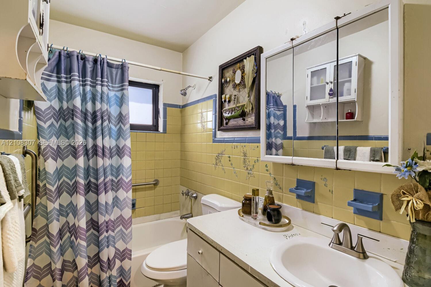 Bathroom featuring tile wall surfacing, a medicine cabinet with integrated mirrors, an inset sink, and a combination tub and shower