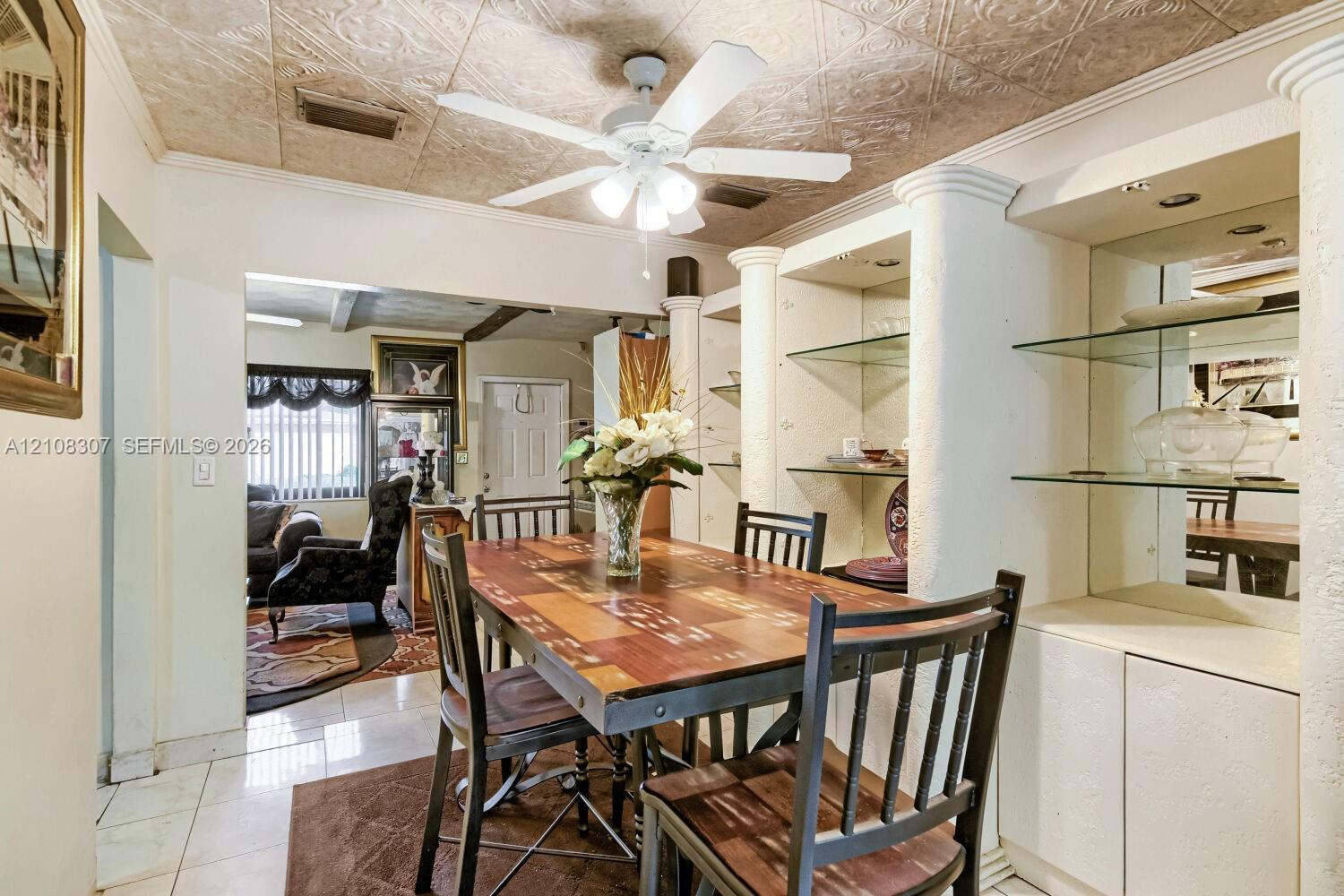 Textured ceiling with decorative pattern, integrated shelving units with glass display tiers, mirrored back panels, and structural columns Textured ceiling with decorative pattern, integrated shelving units with glass display tiers, mirrored back panels, and structural columns