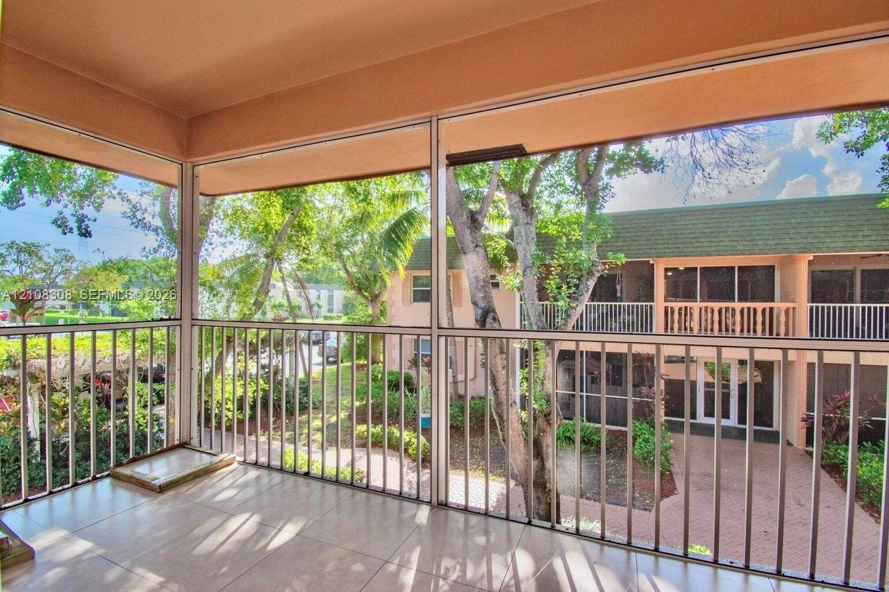 Screened balcony featuring light-toned tile flooring, metal frame enclosures, and vertical railings