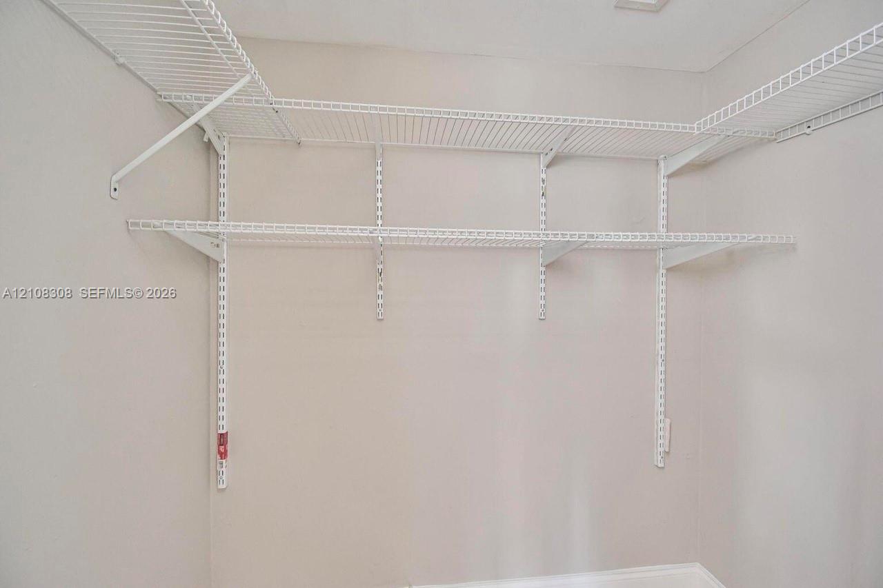 Wall-mounted white wire shelving system featuring tiered storage levels and adjustable support tracks