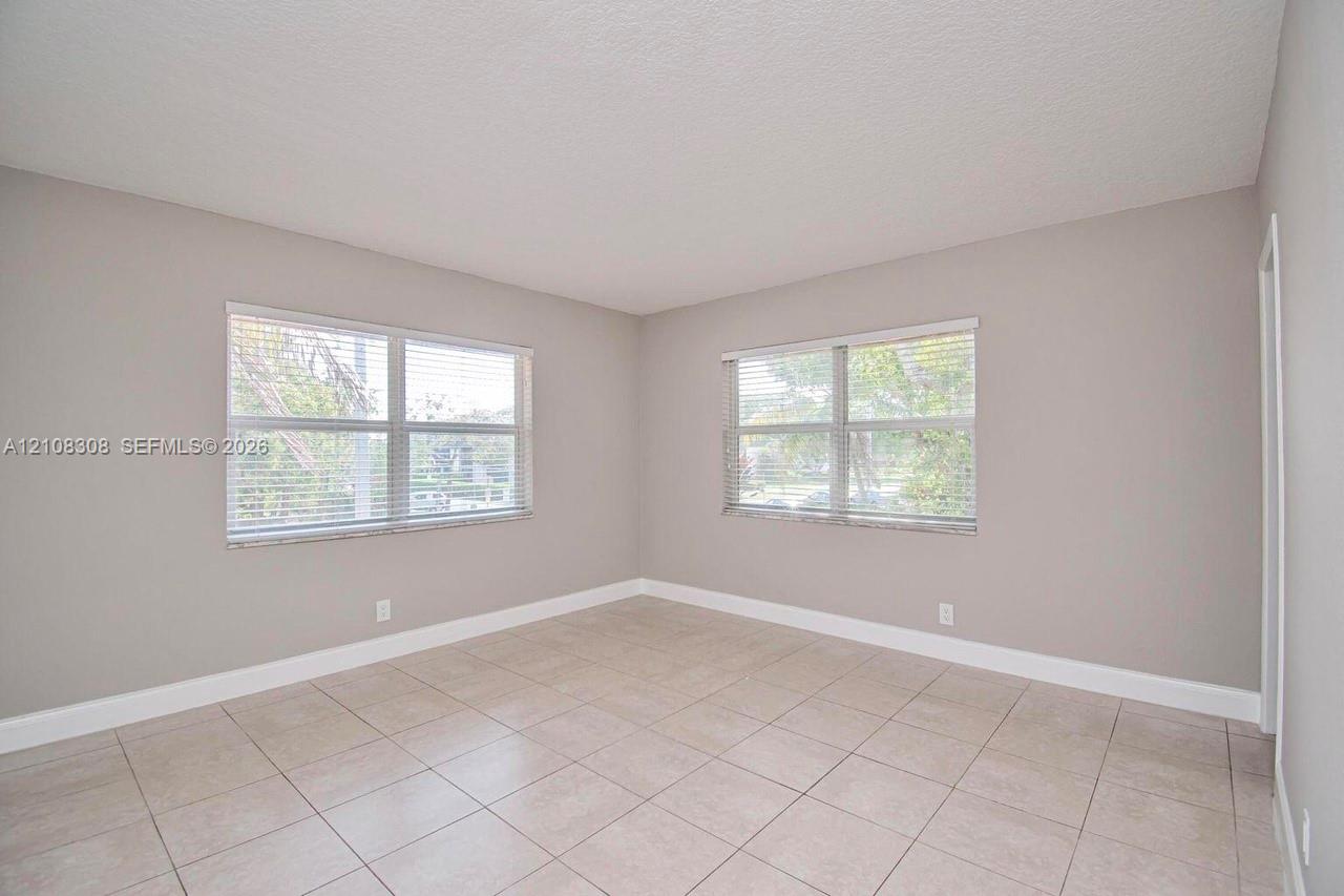 Neutral-toned interior featuring large windows, light-colored tile flooring, and a textured ceiling finish