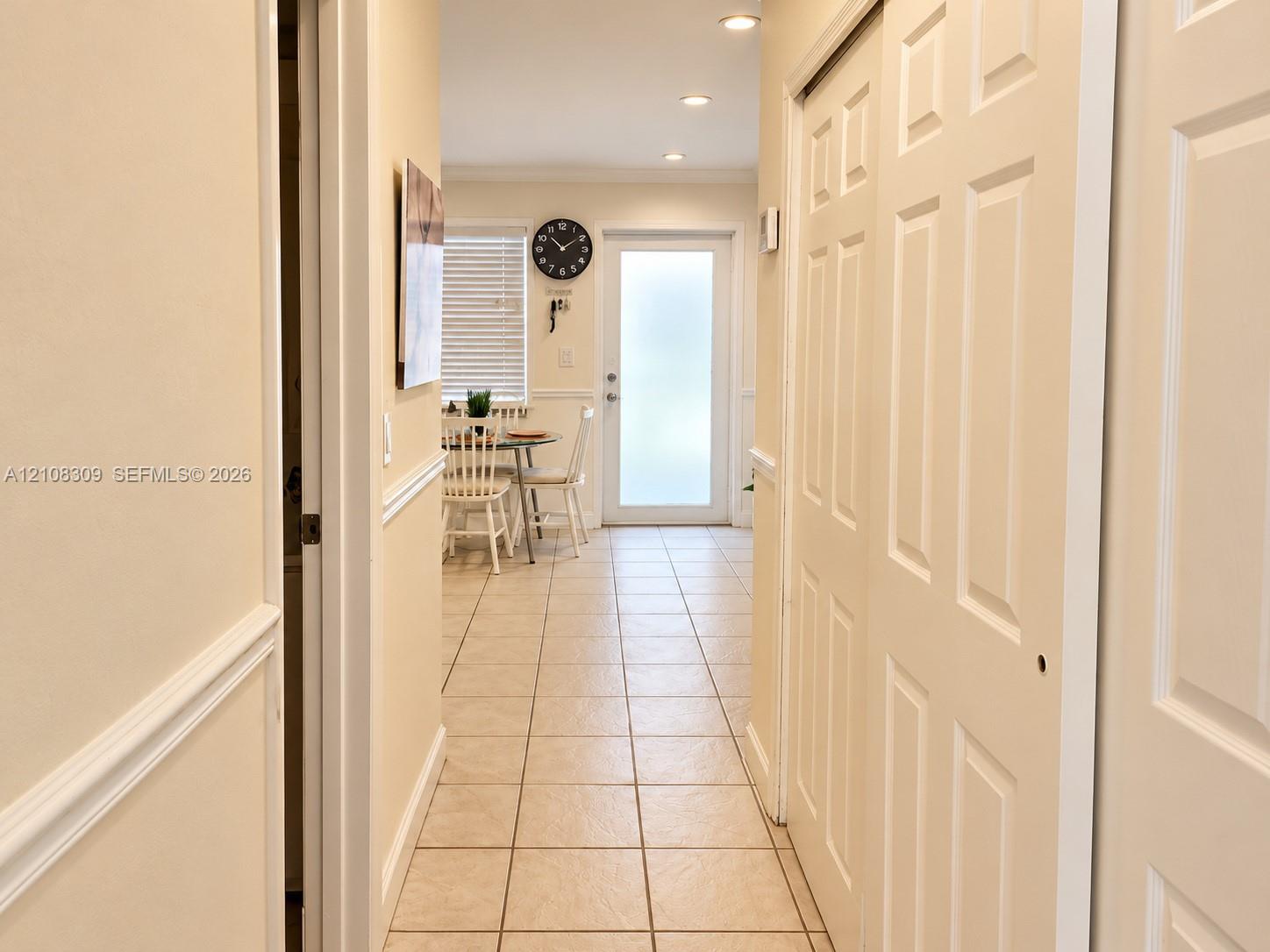 Interior hallway featuring tile flooring, recessed lighting, chair rail molding, and a paneled sliding closet door, finished with a glass-paneled exterior door