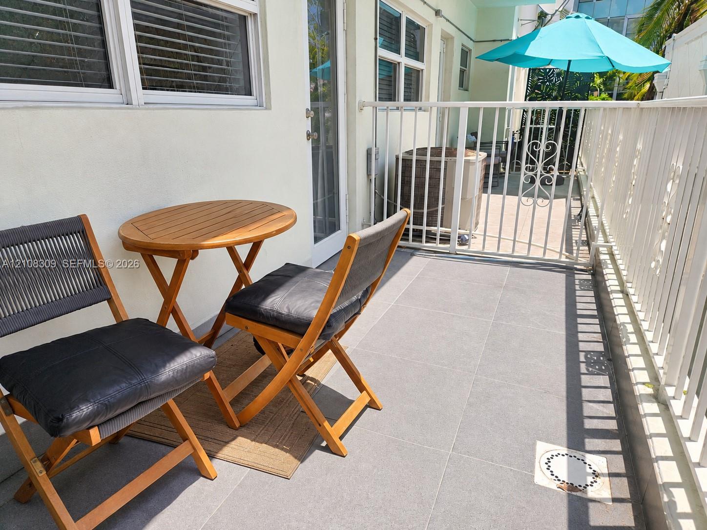 Private patio featuring large-format tile flooring and a perimeter white metal railing Private patio featuring large-format tile flooring and a perimeter white metal railing