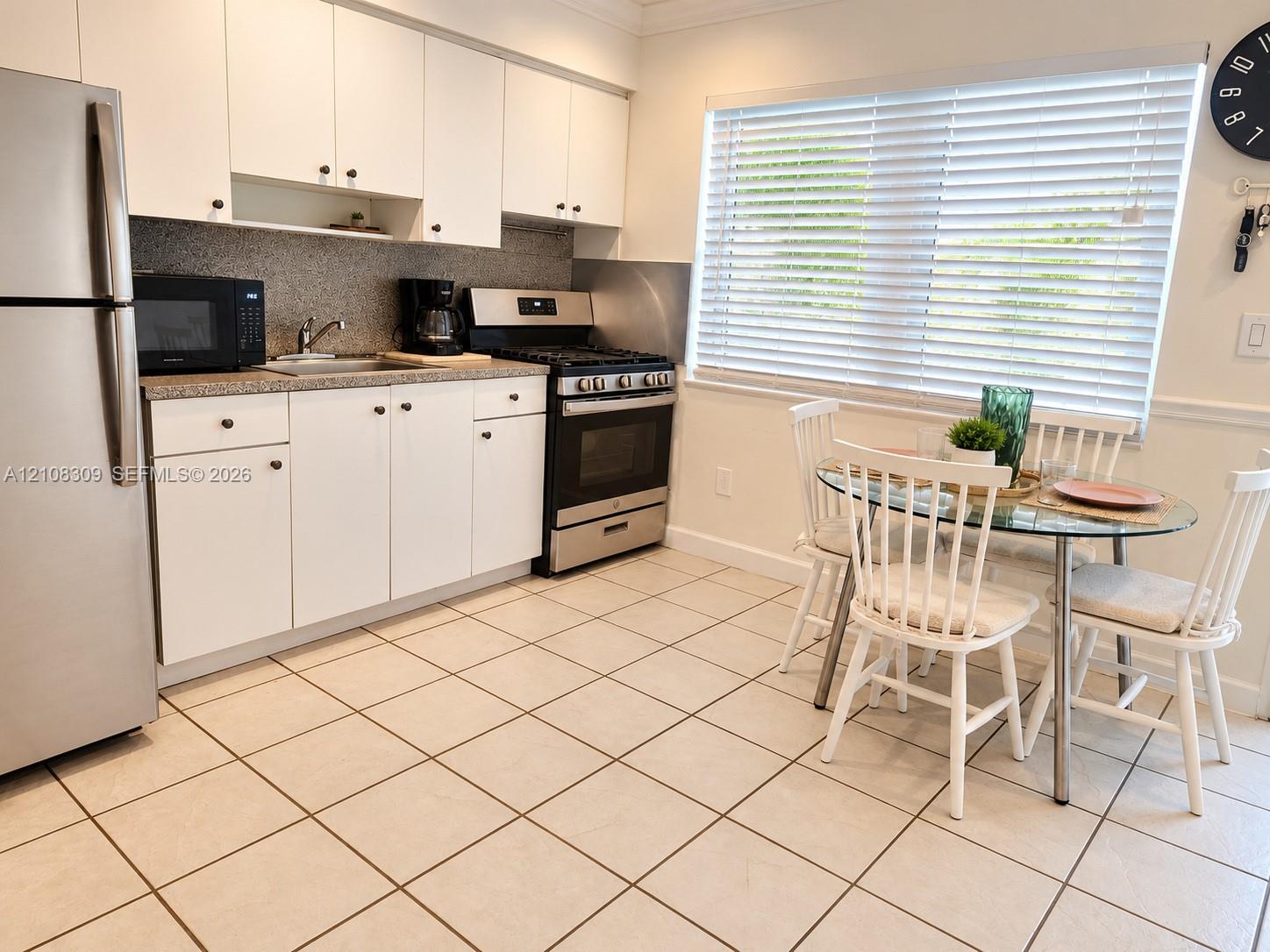 Kitchen featuring white cabinetry, stone-finish countertops, stainless steel appliances, and tile flooring Kitchen featuring white cabinetry, stone-finish countertops, stainless steel appliances, and tile flooring