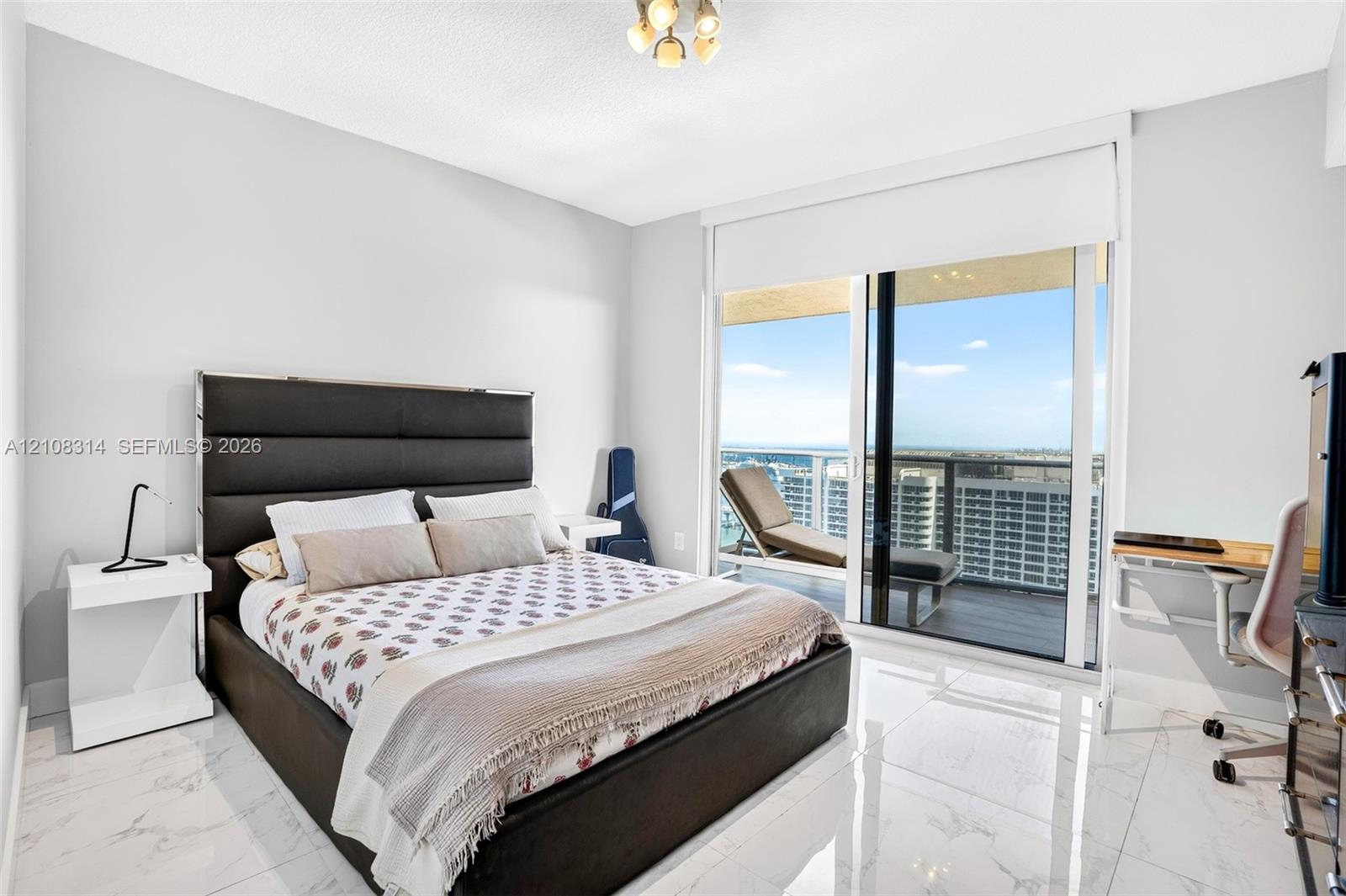 Floor-to-ceiling sliding glass doors, white large-format stone-finish flooring, and recessed ceiling lighting