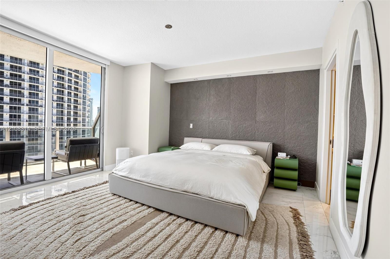 Floor-to-ceiling glass sliding doors, polished tile flooring, and a textured charcoal accent wall featuring recessed integrated lighting