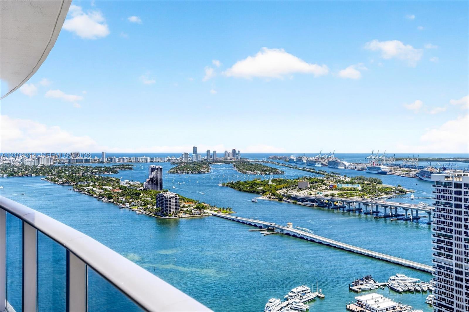 Elevated balcony featuring a glass panel railing and panoramic water-facing vistas of the coastline, islands, and metropolitan skyline