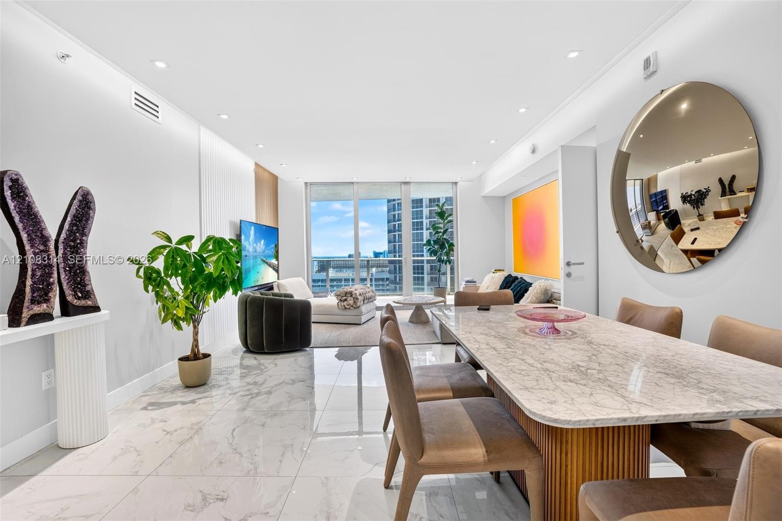 Open-concept living space featuring large-format polished stone flooring, recessed ceiling lighting, and floor-to-ceiling glass windows Open-concept living space featuring large-format polished stone flooring, recessed ceiling lighting, and floor-to-ceiling glass windows