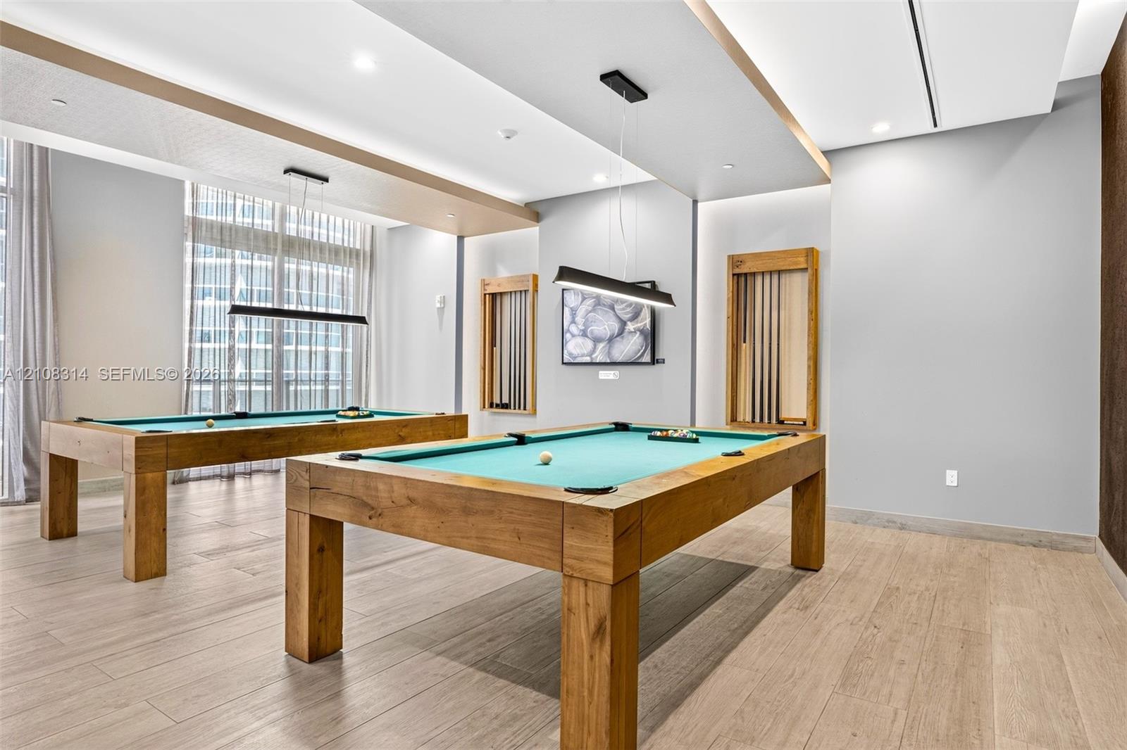 Recessed tray ceilings with integrated lighting, wood-finish flooring, and built-in wall-mounted cue racks