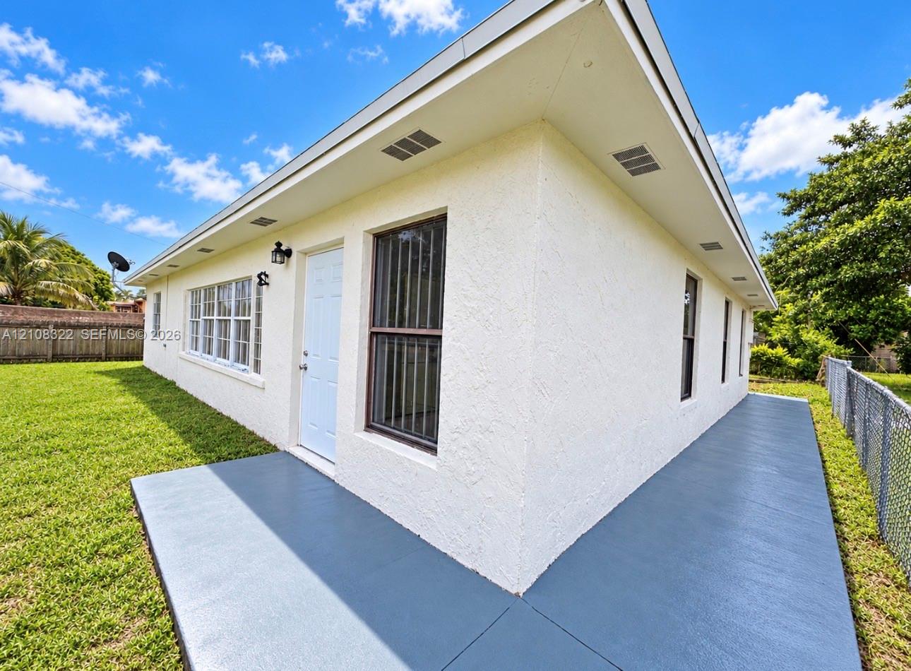Exterior featuring a textured stucco finish, painted concrete patio, white door, multi-pane windows, and inset soffit lighting Exterior featuring a textured stucco finish, painted concrete patio, white door, multi-pane windows, and inset soffit lighting