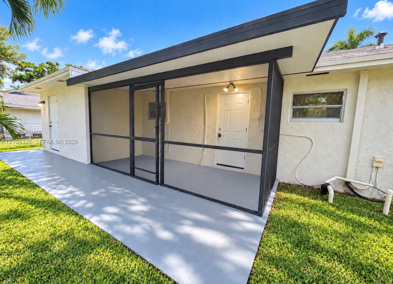 Screened-in patio with a concrete floor, exterior lighting, and painted masonry siding Screened-in patio with a concrete floor, exterior lighting, and painted masonry siding