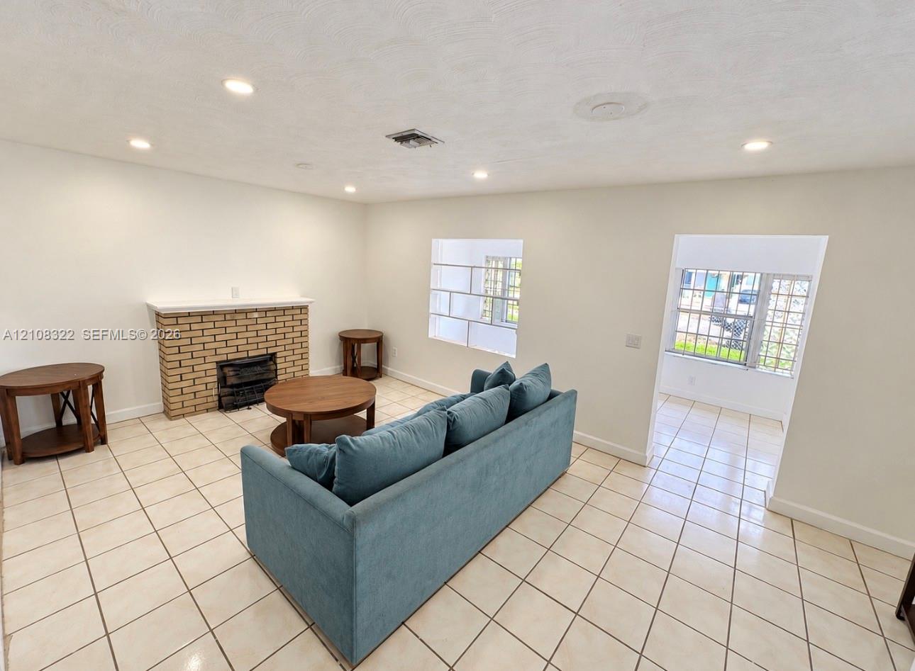 Brick fireplace with a mantel, grid-pattern window, recessed lighting, and tile flooring