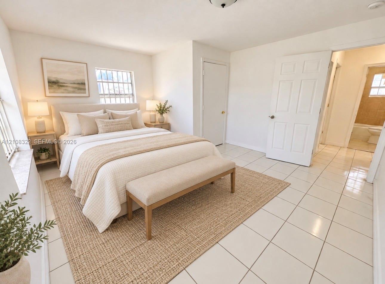 Neutral-toned interior space featuring light-colored ceramic tile flooring, multiple windows providing natural light, and a six-panel interior door