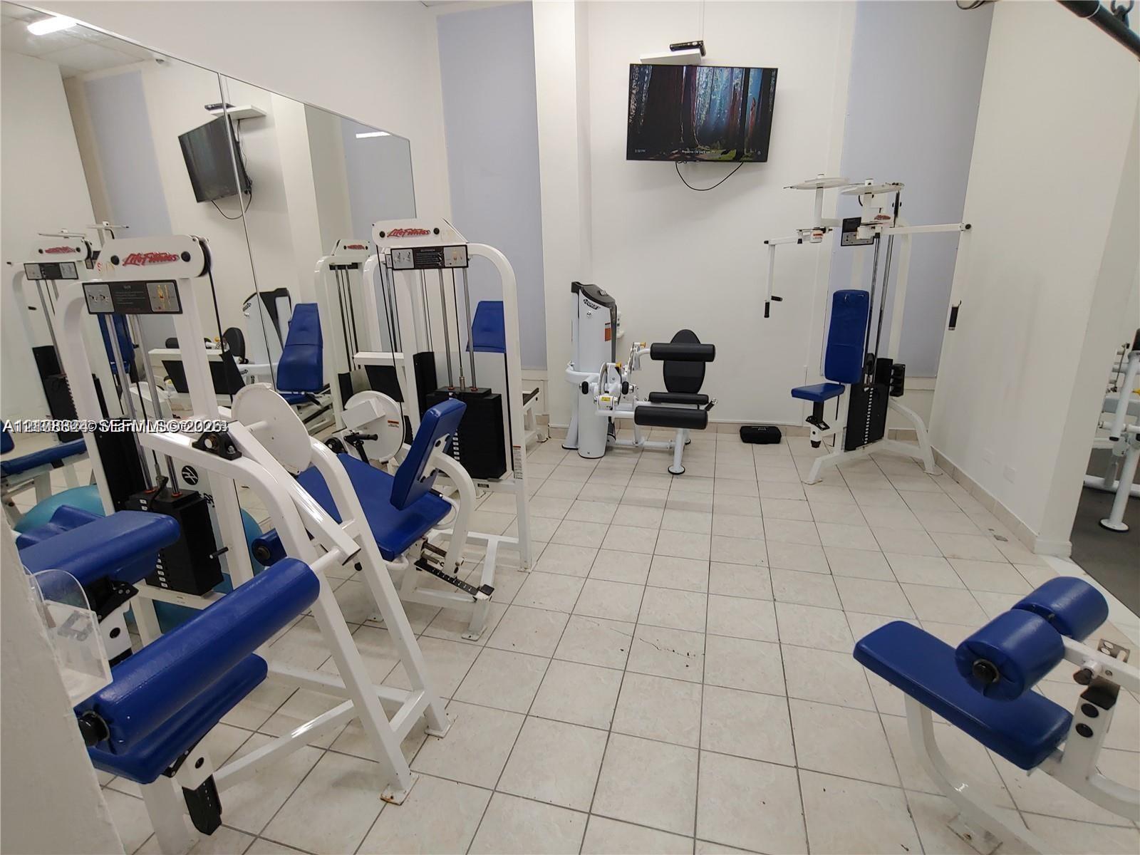 Fitness center featuring large wall-mounted mirrors and ceramic tile flooring