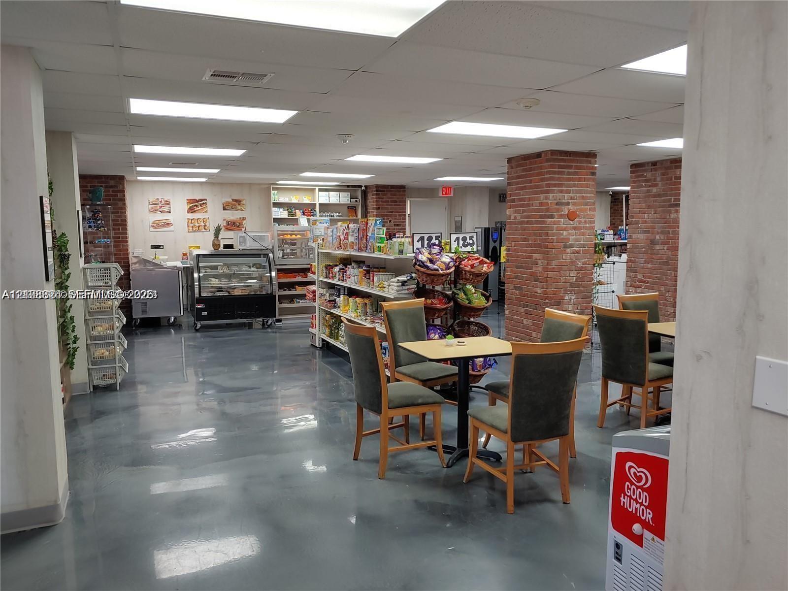 Expansive open-concept commercial space featuring high-gloss epoxy flooring, exposed brick support columns, integrated recessed ceiling lighting, and built-in service counters