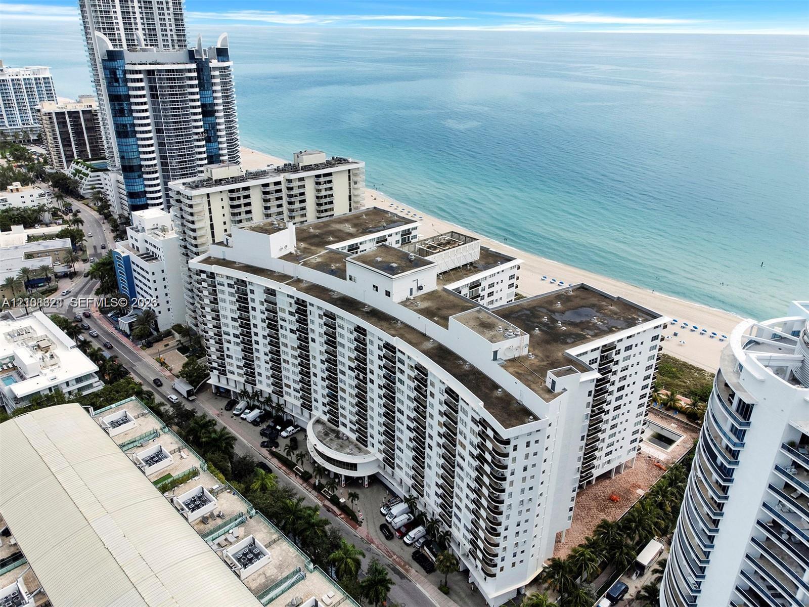 Mid-rise coastal residential building featuring a curved architectural design, private exterior balconies, and direct proximity to the oceanfront