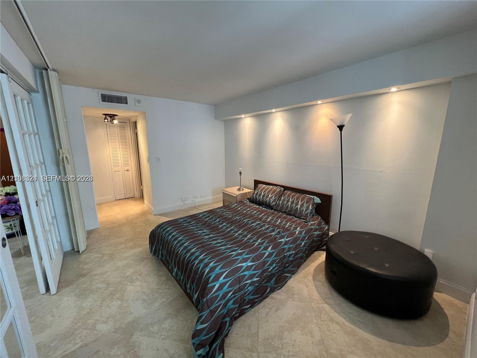 Interior space featuring neutral stone-finish tile flooring, recessed cove lighting, and French-style glass pane double doors