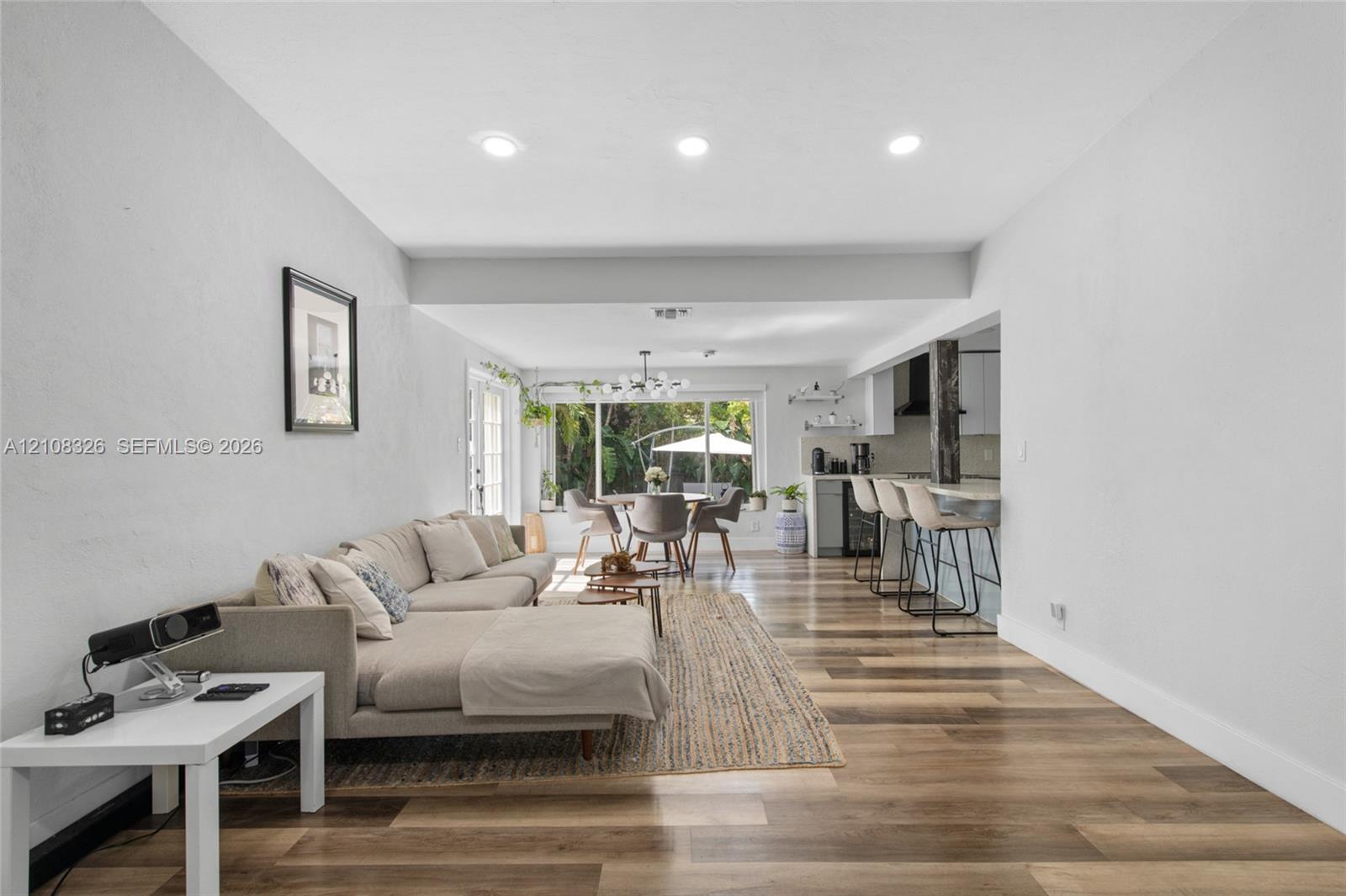 Open-concept interior featuring wood-finish flooring, recessed lighting, and a kitchen equipped with a breakfast bar Open-concept interior featuring wood-finish flooring, recessed lighting, and a kitchen equipped with a breakfast bar
