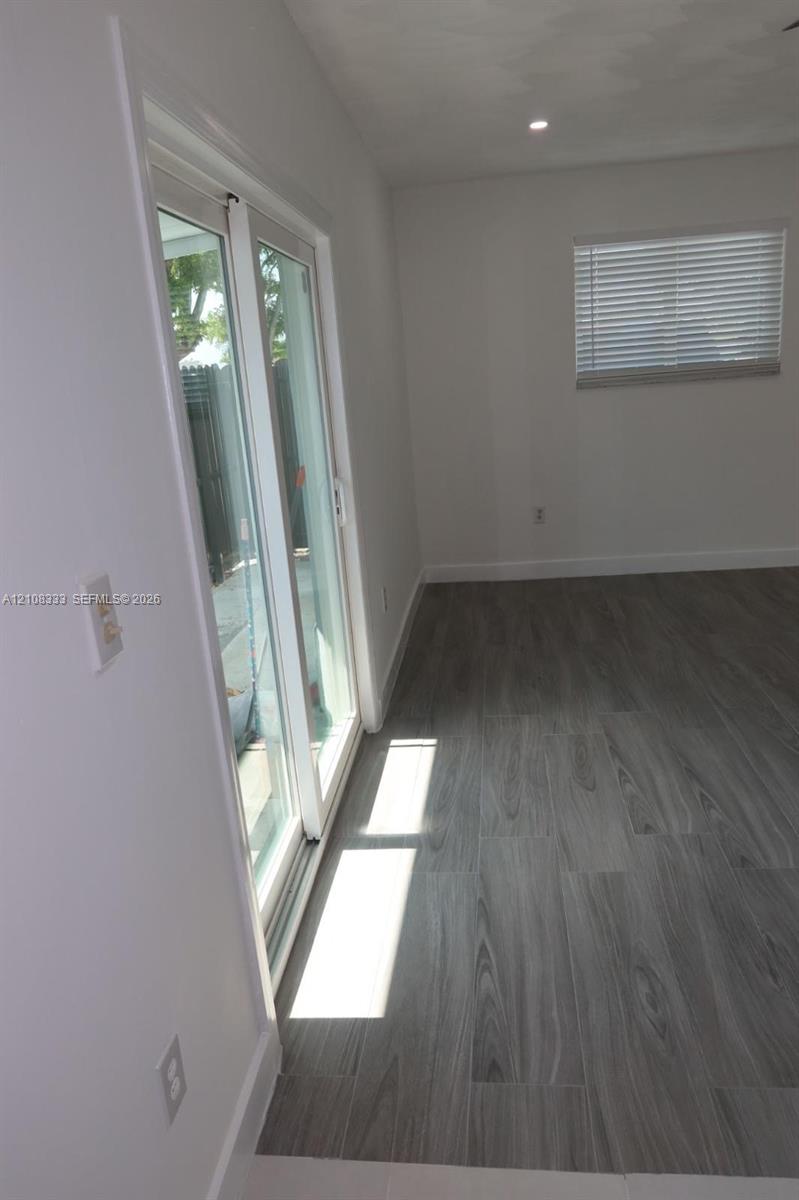 Wood-finish flooring, sliding glass door, recessed ceiling lighting, and horizontal window blinds