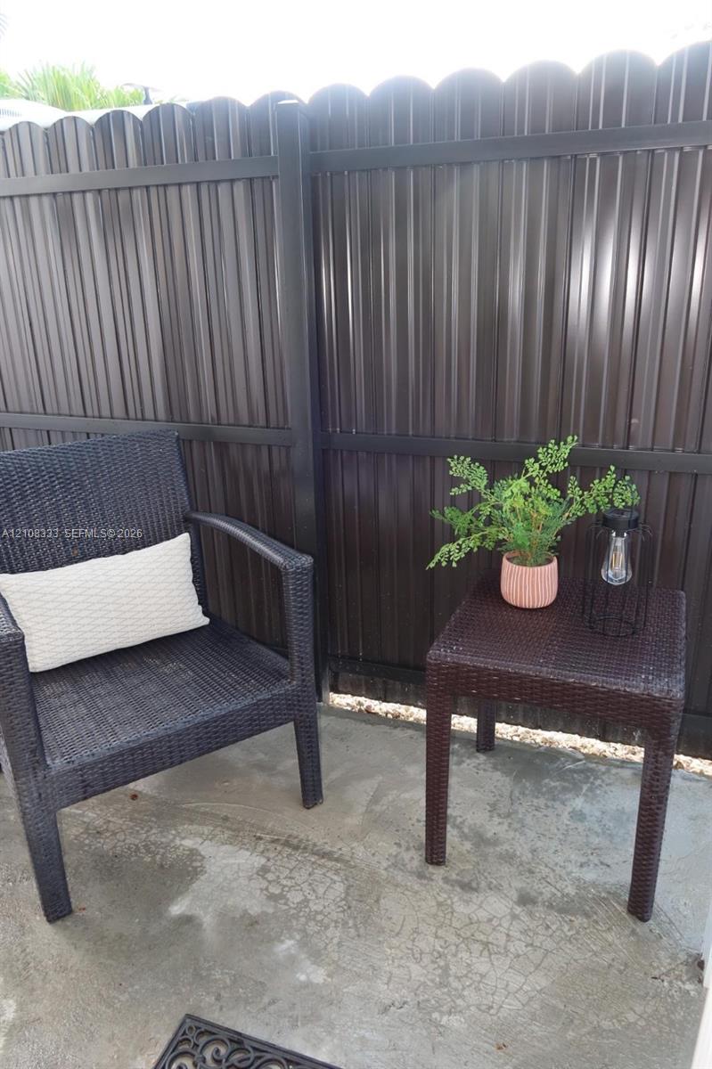 Concrete patio enclosed by a dark-finished scalloped privacy fence
