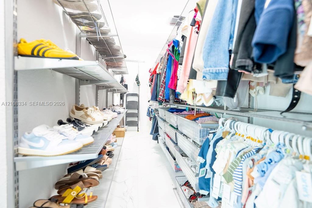 Walk-in closet featuring adjustable metal shelving, tiered wire racking, and integrated pull-out storage baskets