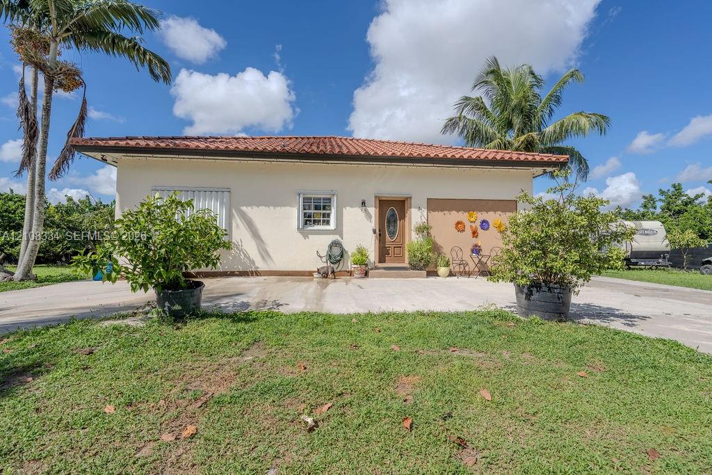 Single-story exterior featuring a clay tile roof, stucco finish, attached garage, and concrete driveway