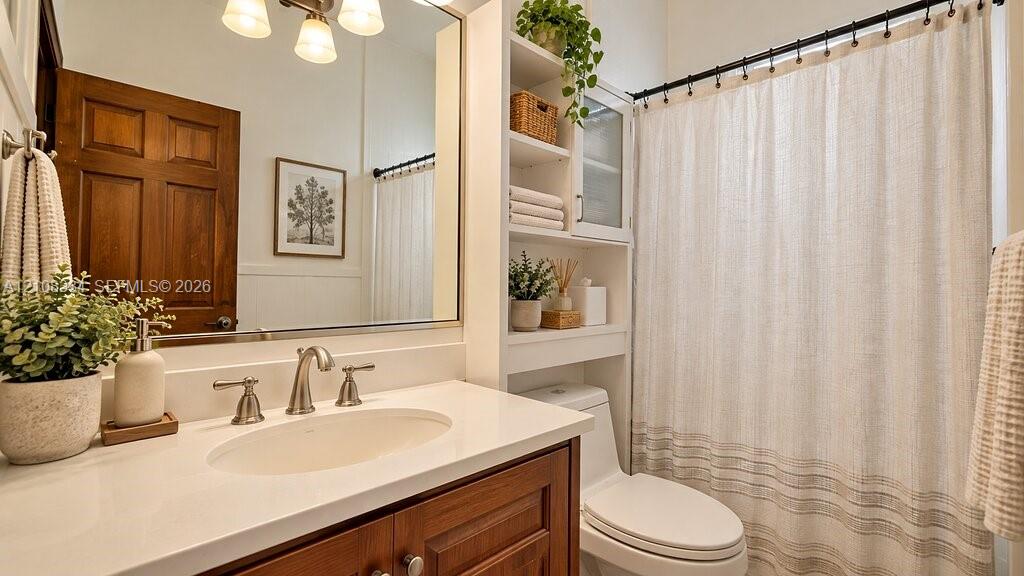 Bathroom featuring a vanity with a white solid-surface countertop, an oval undermount sink, brushed-nickel faucet hardware, built-in shelving, and a large wall-mounted mirror