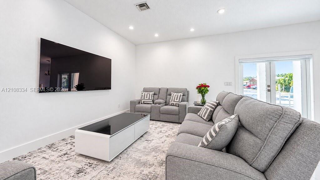 Neutral color palette featuring recessed lighting, a wall-mounted display, and glass-paned exterior doors