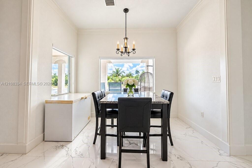 Large-format porcelain tile flooring with veining, crown molding, built-in cabinetry with a smooth-finish surface, and a multi-light iron chandelier
