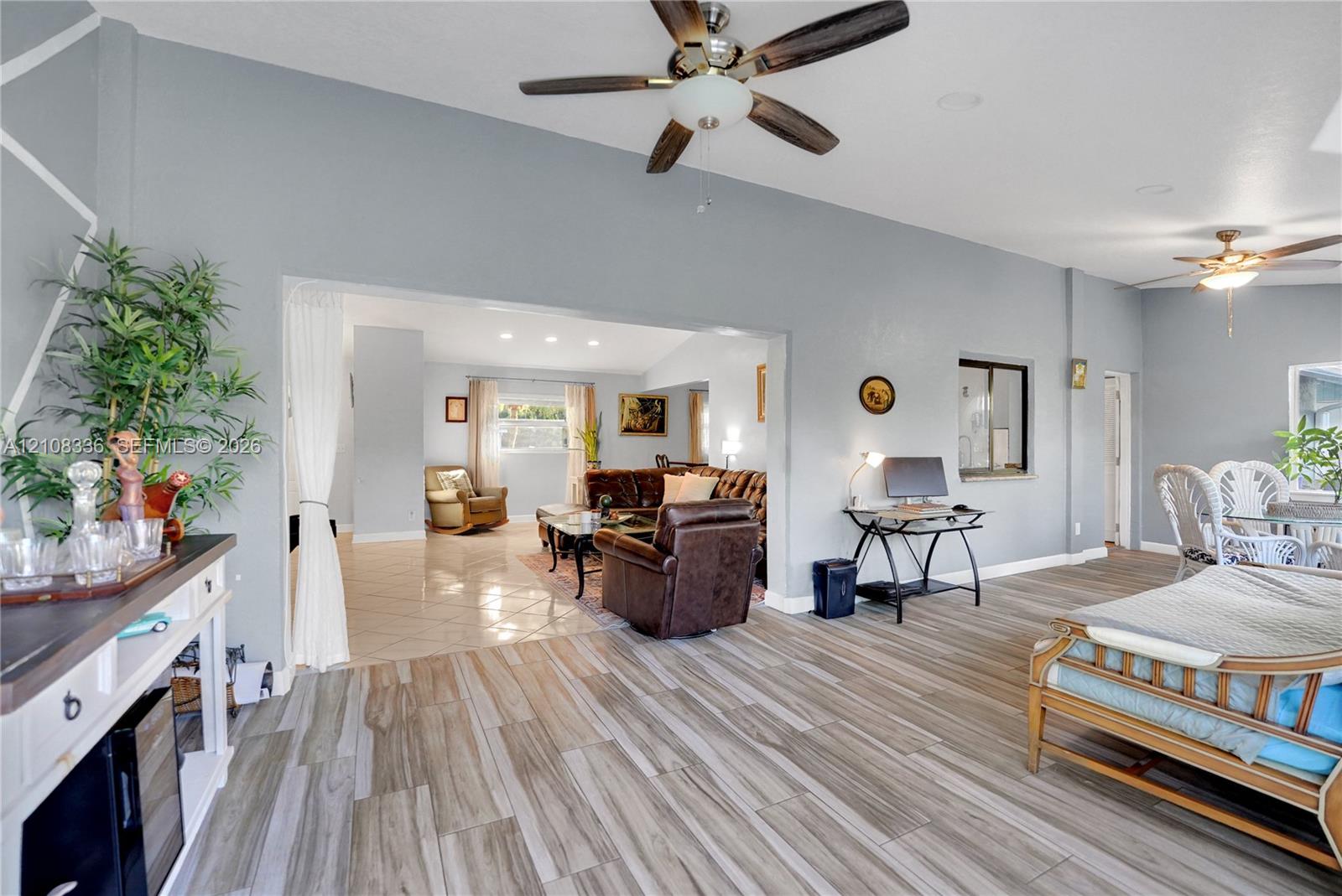 Open-concept interior featuring wood-finish flooring, vaulted ceilings, dual ceiling fans, and neutral wall tones