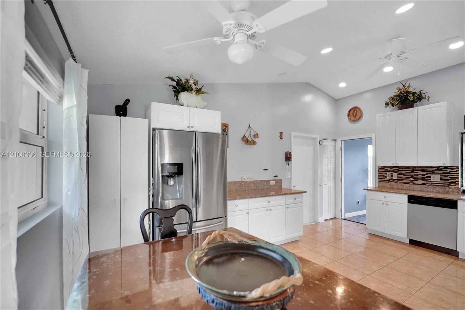 Kitchen featuring white cabinetry, stone-finish countertops, tile flooring, recessed lighting, and stainless steel appliances