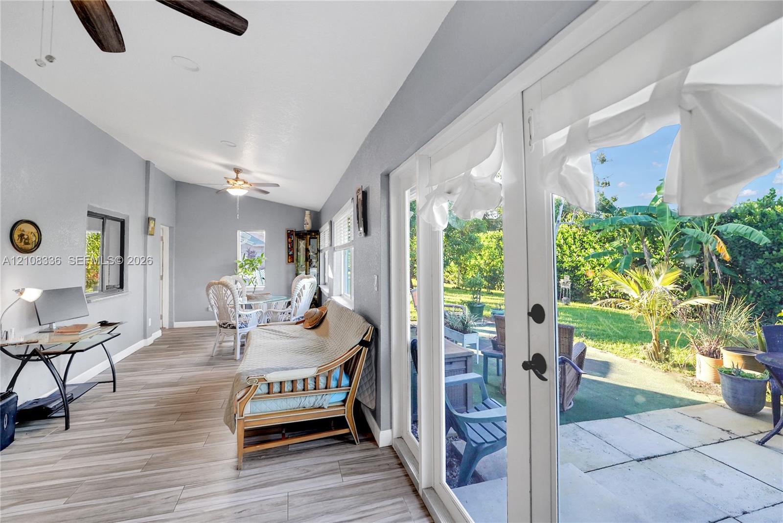 Sunroom featuring wood-finish flooring, recessed lighting, dual ceiling fans, and full-length glass panel doors opening to a paved patio
