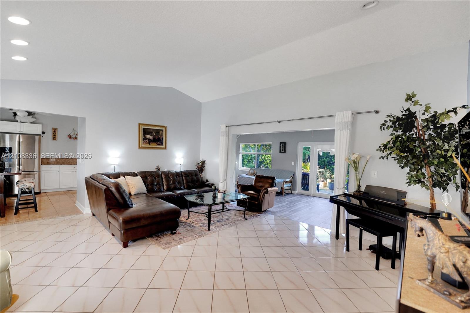Open-concept interior featuring vaulted ceilings, neutral wall tones, large-format tile flooring, and recessed lighting