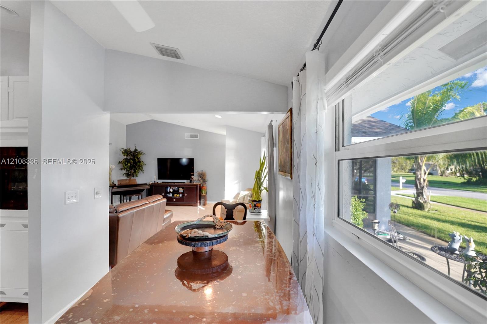 Vaulted ceilings, large picture window with natural light, and neutral wall color palette